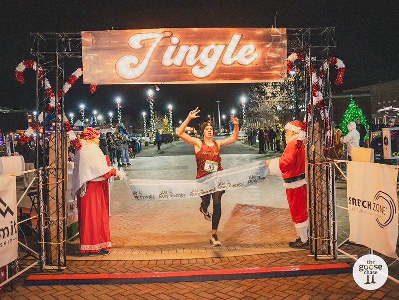 A runner crosses the finish line beneath a Jingle banner at a past event